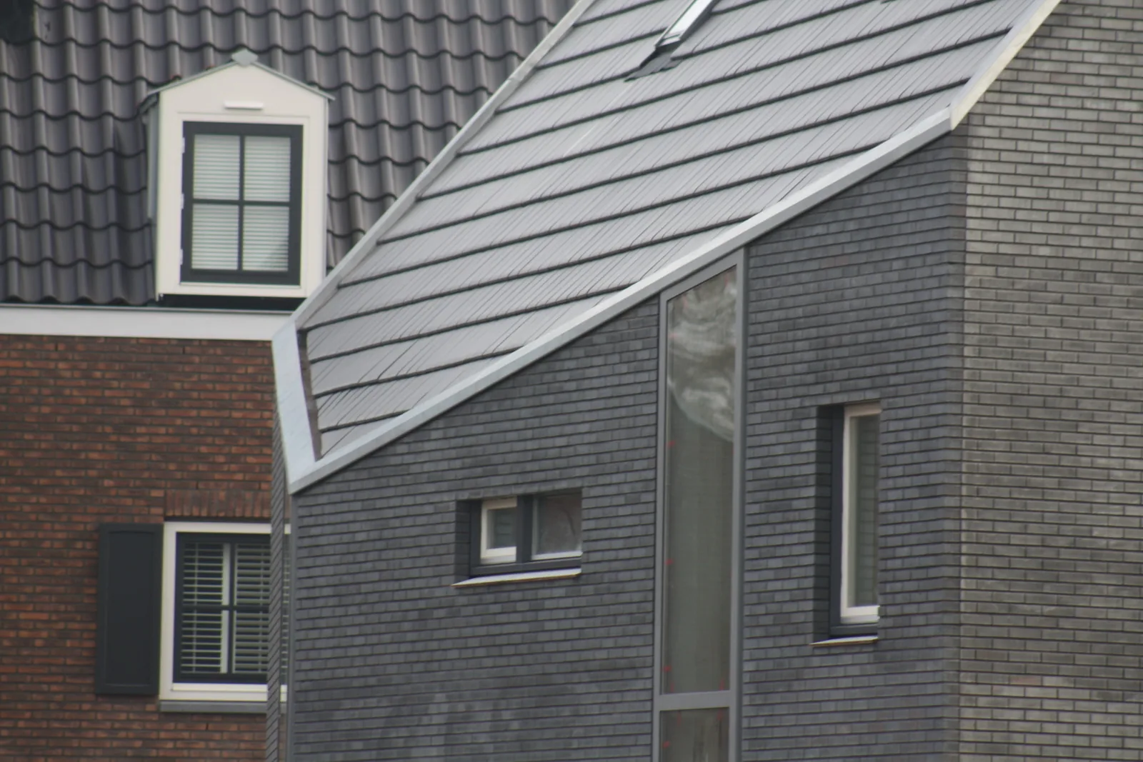 Abstracte gevel knikhuis met strak geplaatste kozijnen en verdraaide kap