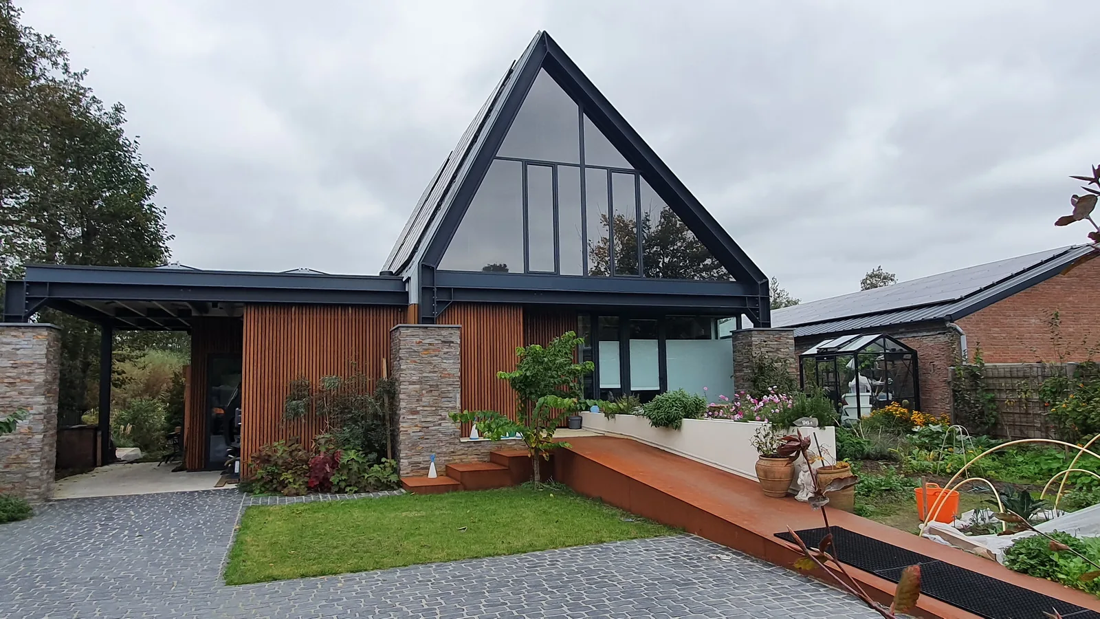 Cortenstalen hellingbaan als entree naar de verhoogd gelegen woning.